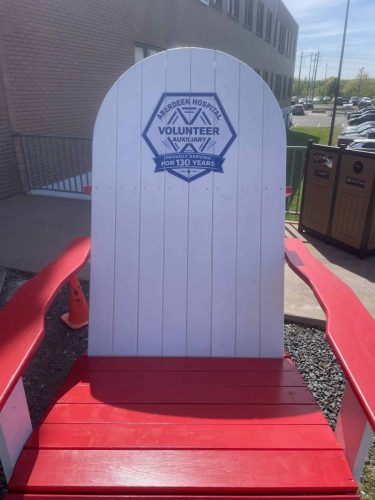 Large red and white Adirondack chair featuring an Aberdeen Hospital Volunteer Auxiliary graphic celebrating 130 years of service.