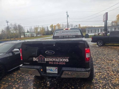 Rear view of a black Ford F-150 truck with BG Renovations logo, slogan “Putting Your Dreams to Work,” and phone number on the tailgate and back rack, designed by Auto Trim  Signs in New Glasgow.