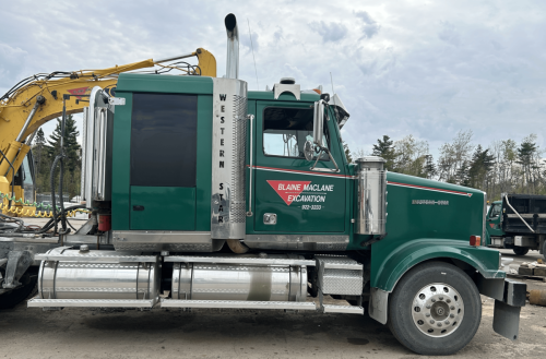 Green Western Star excavation truck with Blaine MacLane Excavation door lettering parked at a work site.
