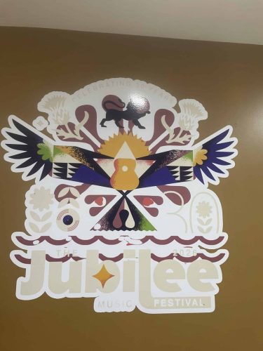 Large colourful Jubilee Music Festival 30th anniversary wall graphic installed indoors featuring festival branding and artwork.