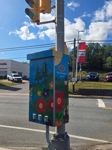 Utility box in New Glasgow wrapped with a bright, colorful design featuring a river, trees, and flowers under a clear blue sky.