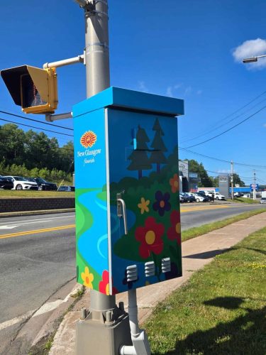 Another view of the New Glasgow utility box with vibrant floral artwork, trees, and a flourish slogan near a traffic light.