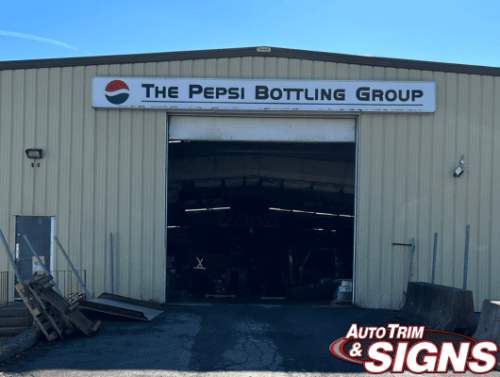 Before image showing the exterior of The Pepsi Bottling Group warehouse with the old signage above the entrance, featuring the company's traditional red, white, and blue logo and lettering on a plain background.