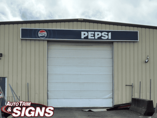 After image displaying the updated and modernized exterior of The Pepsi Bottling Group warehouse, with sleek new signage featuring a bold 'PEPSI' logo in white letters on a deep blue background, accented by a light blue stripe and the circular Pepsi emblem to the left.