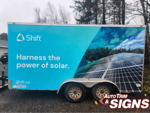 Wide side view of a trailer wrapped in Shift's branding showing a detailed image of solar panels under a clear sky, with the text 'Harness the power of solar.' and the website address.