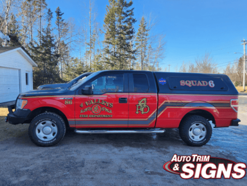 Side view of a red fire department pickup truck with 'SQUAD 6' and 'Valley's Fire Department' graphics in gold and black, along with the department's emblem, all designed by Auto Trim  Signs, parked outdoors on a sunny day.