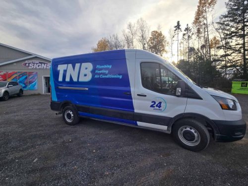 Blue and white service van with TNB Plumbing, Heating  Air Conditioning branding and “24 Hours” logo, parked outside Auto Trim & Signs in New Glasgow.