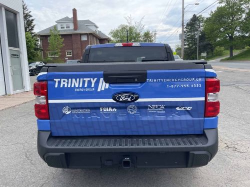Rear view of a Trinity Energy Group truck featuring custom tailgate graphics with company branding, website, phone number, and industry association logos.