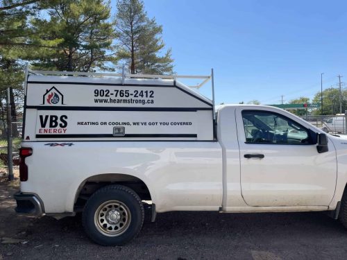 Side view of a VBS Energy service truck with custom branding, logo, website, phone number, and service message displayed on the utility body.