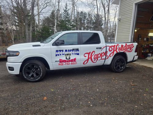 White pickup truck wrapped with Atlantic Dodge branding on the door and large red “Happy Holidays” lettering along the side.
