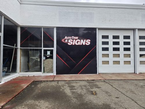 Close-up of the new Auto Trim  Signs storefront panel featuring a black and red graphic design installed on the building during renovations.