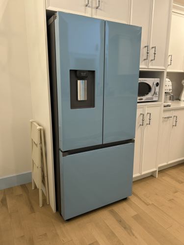 Kitchen fridge wrapped in glossy soft blue vinyl to match surrounding appliances and cabinetry.