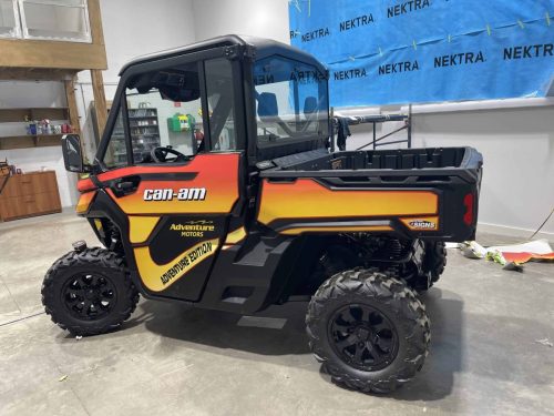 Front view of wrapped Can-Am side-by-side with black orange and yellow custom graphics