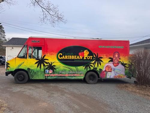 Front and side angle of the Caribbean Pot food truck with a palm tree and sunset wrap design and the words “CLOSED” on the side window.