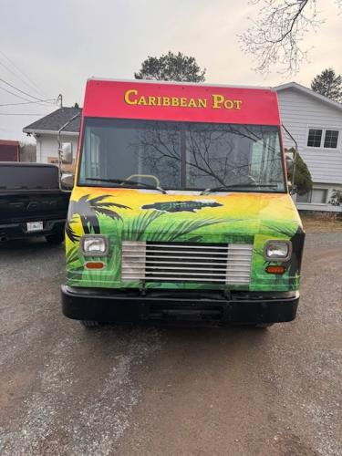 Head-on view of the Caribbean Pot food truck with red and yellow branding and palm tree graphics across the hood.