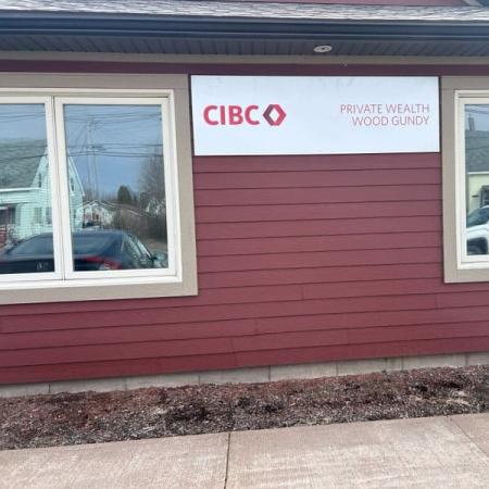 CIBC Private Wealth Wood Gundy sign displayed on the side of a red commercial building with large windows.
