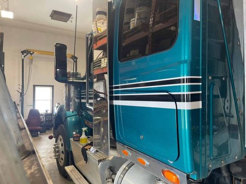 Teal semi truck sleeper cab with black and white custom stripe graphics installed by Auto Trim.