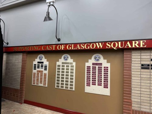 Interior sponsor recognition wall with multiple plaques and “Supporting Cast of Glasgow Square” header