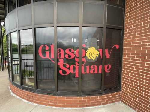 Exterior window graphics for Glasgow Square featuring large red lettering and a gold lion icon applied across tinted glass panels.