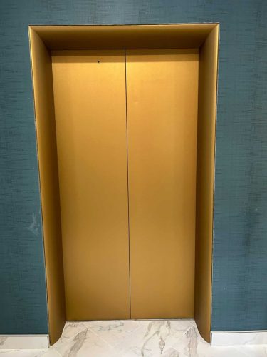 Gold vinyl wrapped elevator doors installed by Auto Trim in a hallway.