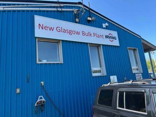 Exterior view of a blue metal building with a newly installed Irving sign reading “New Glasgow Bulk Plant” above three windows.
