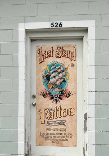 Custom door graphic for Last Stand Tattoo featuring ship illustration and contact details