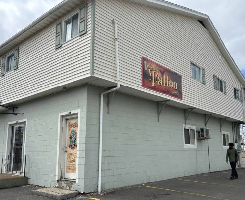 Exterior view of Last Stand Tattoo building with large wall-mounted sign on upper level