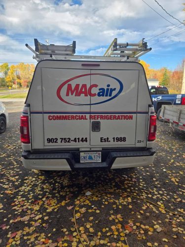 Rear view of MACair service truck showing company branding, phone number, and establishment date.