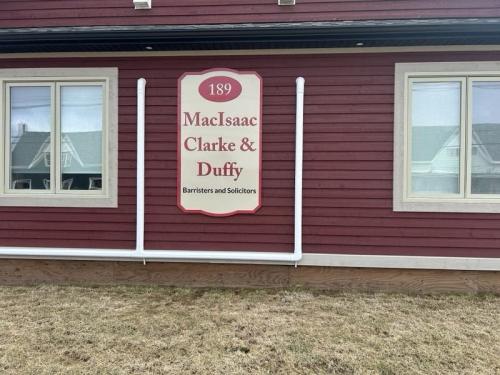 Exterior sign for MacIsaac Clarke  Duffy, Barristers and Solicitors, mounted on a red building with cream trim.