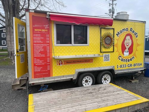 Full side view of Mama Red’s Canteen food truck showing the entire menu board on the door, serving window with red awning, and sunflower wall décor.