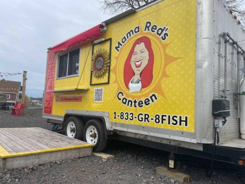 Side view of Mama Red’s Canteen food truck featuring the large logo, caricature of Mama Red, and bold phone number 1-833-GR-8FISH.
