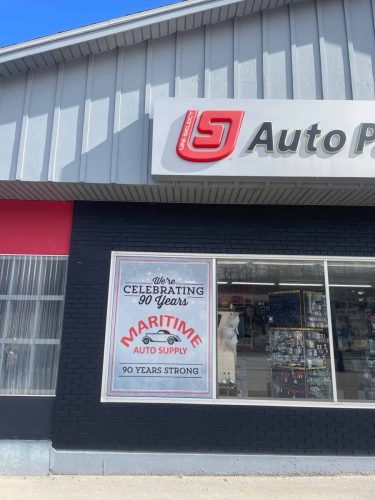 Close-up of Maritime Auto Supply window graphic celebrating 90 years with bold lettering and design