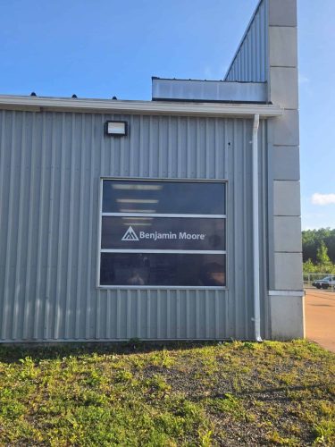 Exterior view of a commercial window with a Benjamin Moore logo graphic installed on tinted or perforated vinyl at Trinity Tools  Interiors.