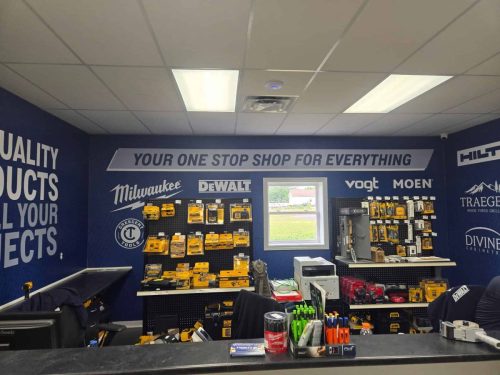 Wide-angle view of the Trinity Tools  Interiors service area showing the branded wall graphic behind the counter and product displays.