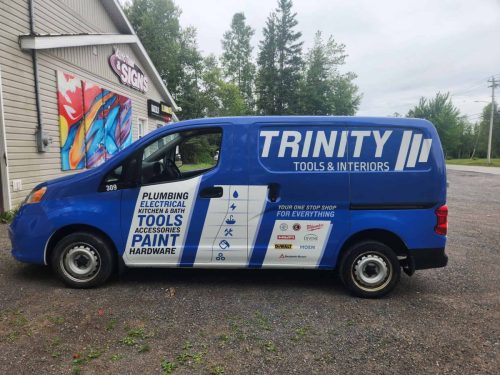 Trinity Tools  Interiors delivery van viewed from the passenger side, with vibrant graphics promoting product categories, service offerings, and supplier branding.