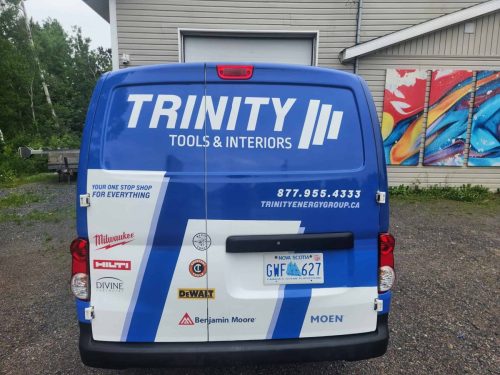 Back view of a branded Trinity Tools  Interiors van featuring logo, contact information, and partner product logos on a blue and white wrap design.