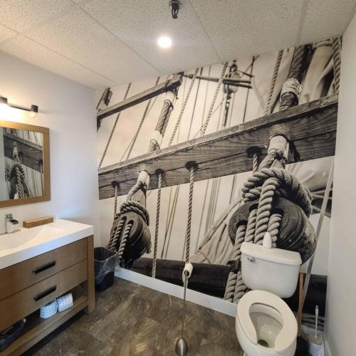 A bathroom with a large, black-and-white nautical-themed wall wrap showing ropes and wooden beams from a ship, adding depth and character to the space.